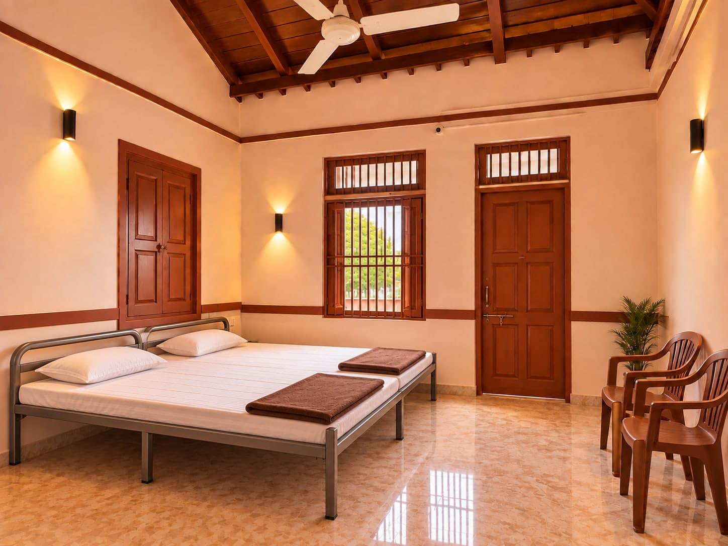 Guest room with steel beds and clean white bedding, a ceiling fan, wooden windows and door, and seating